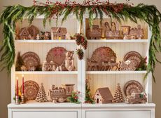 a dresser filled with ceramic gingerbread christmas decor with a garland draped above