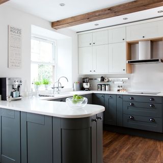 kitchen area with white wall and wooden floor and grey counter with white worktop