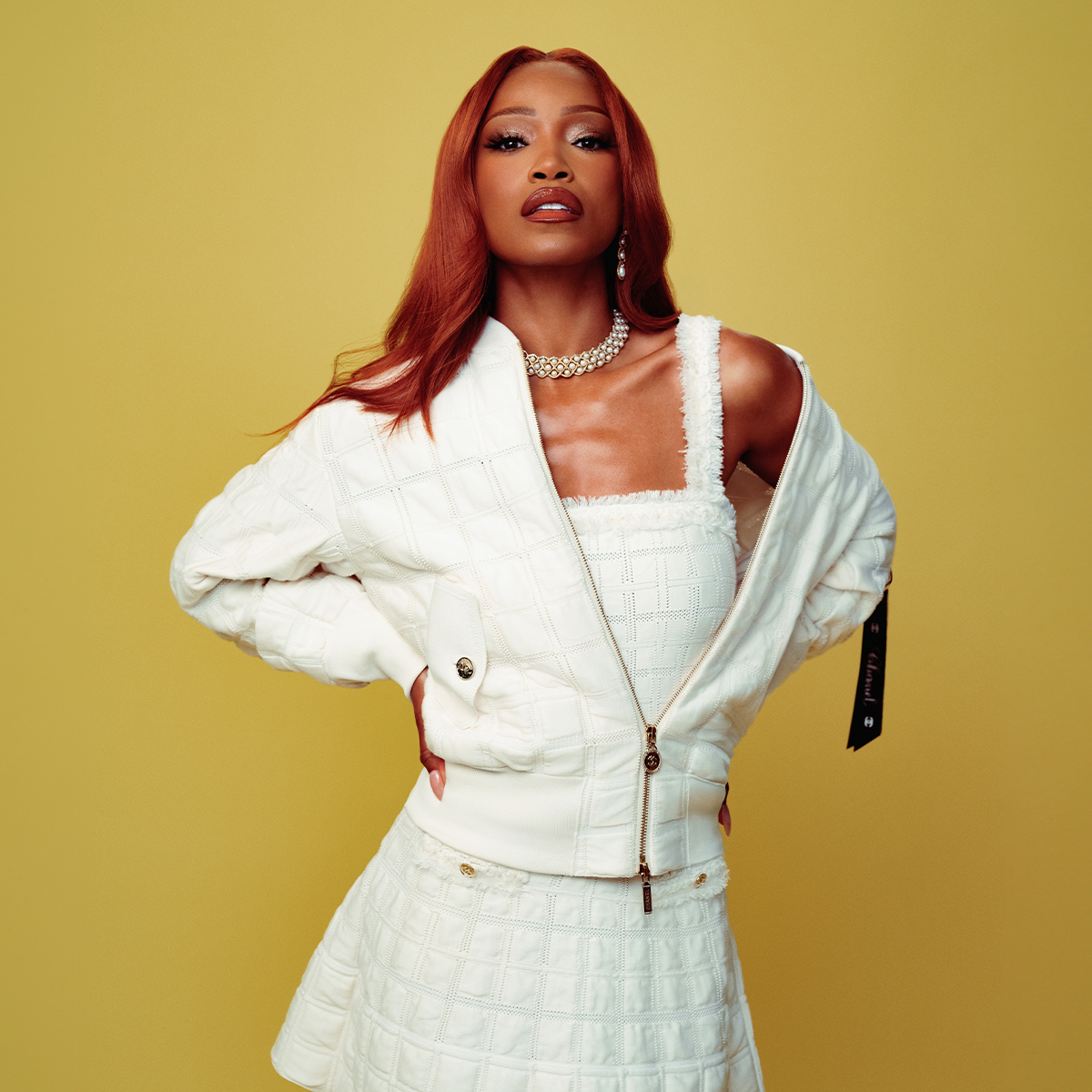 Promo image for Keke Palmer's JulyBest Knockoff Luxury Clothing
 cover story. She is wearing a white matching jacket, top, and skirt set by Chanel with a diamond and pearl necklace. 