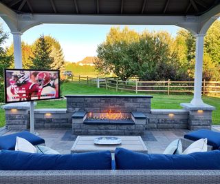 Outdoor tv on stand by couches with view over yard
