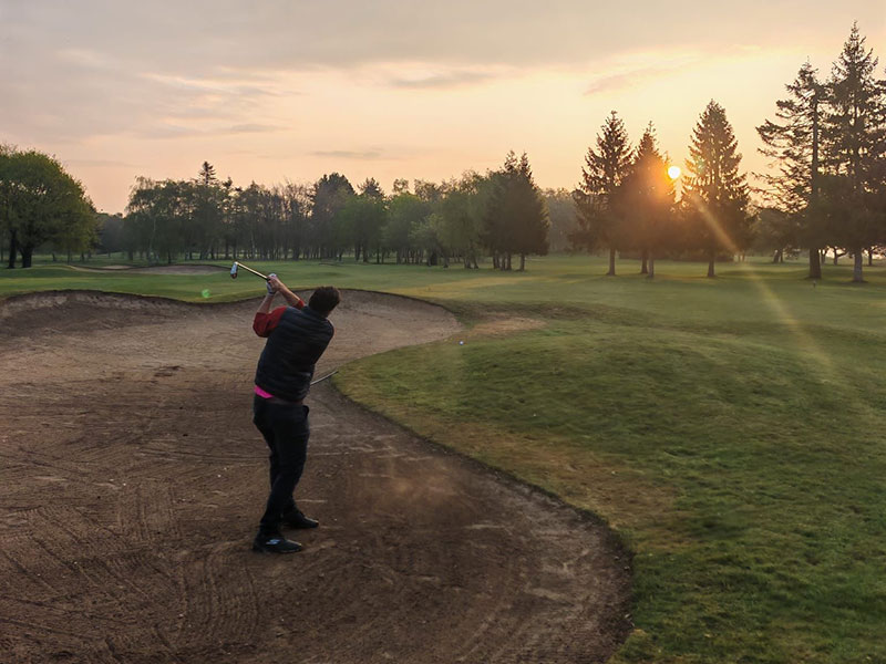 a golfer hitting out of a fairway bunker