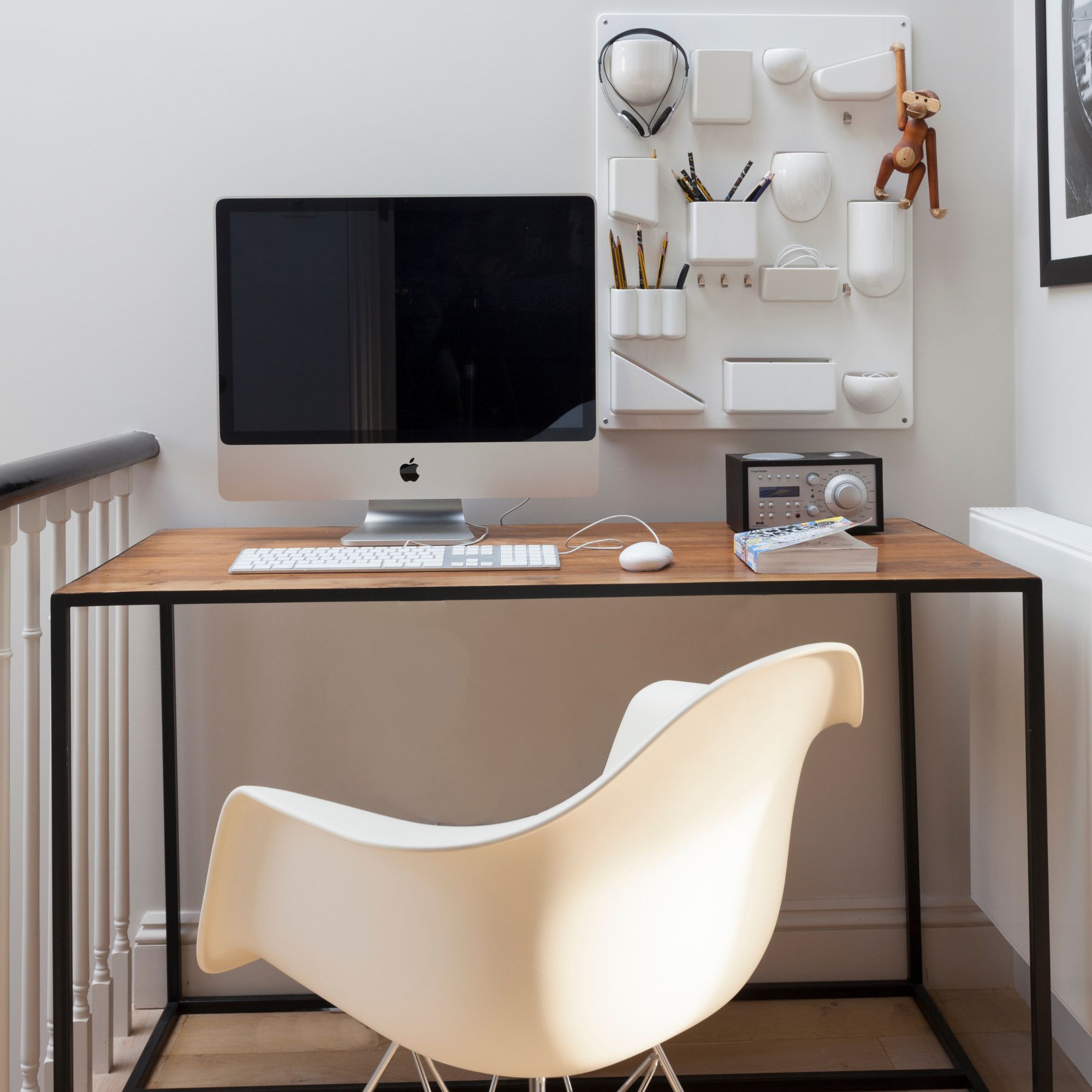 Home office with a wooden desk and a desktop on top of it, and a wall organiser behind it