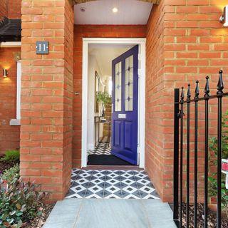 Red brick house with black front grate and blue door