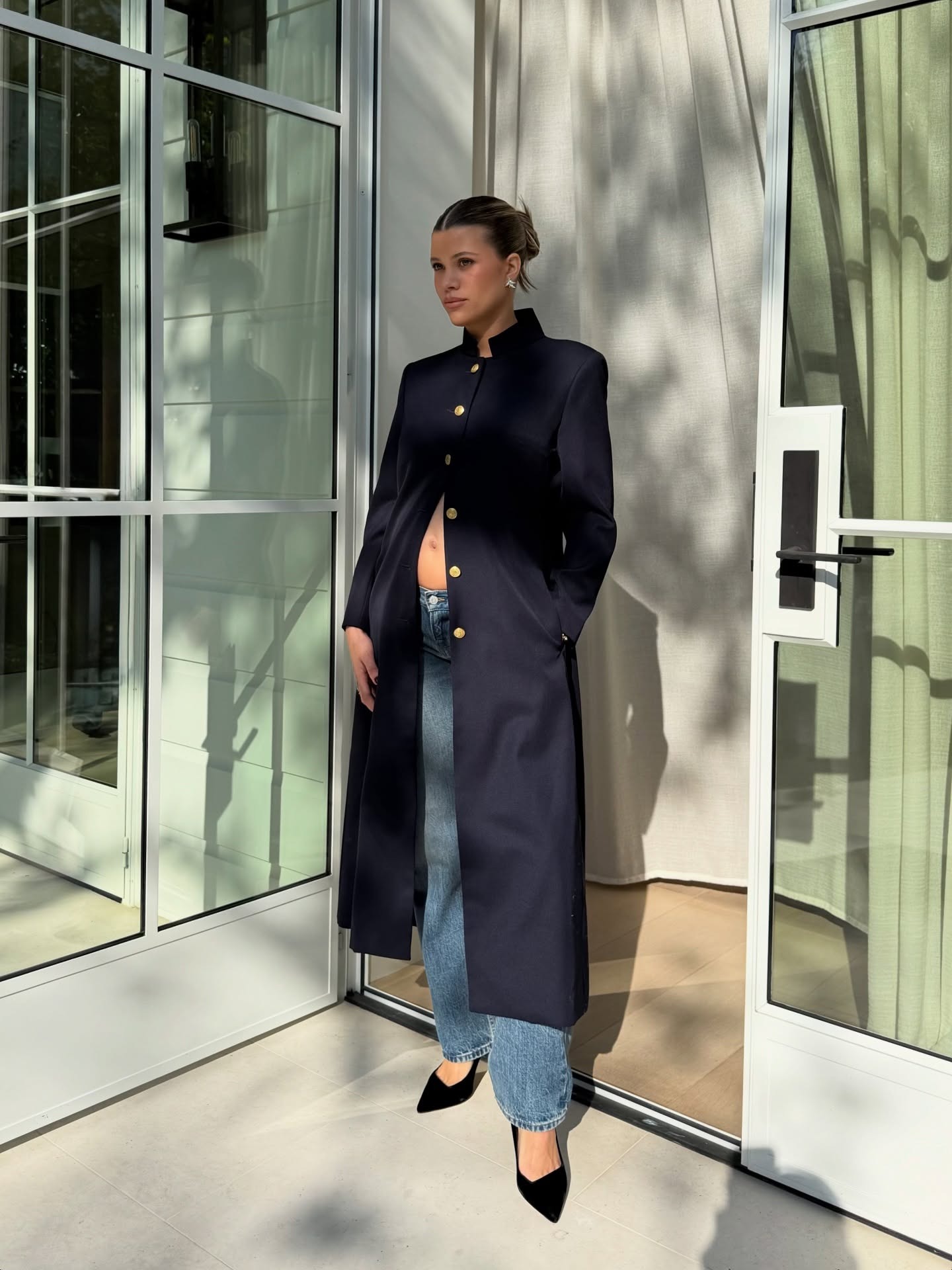 Sofia Richie wearing a navy coat, jeans, and black pumps on her Instagram