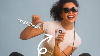A person is showing off the Xreal Beam, it looks like an iPod and is connected to the Xreal glasses they're wearing.