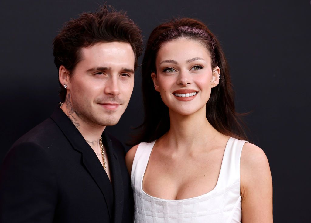 Brooklyn Beckham in a black suit and Nicola Peltz in a white dress at an event