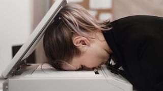A businesswoman with her head resting on an open printer