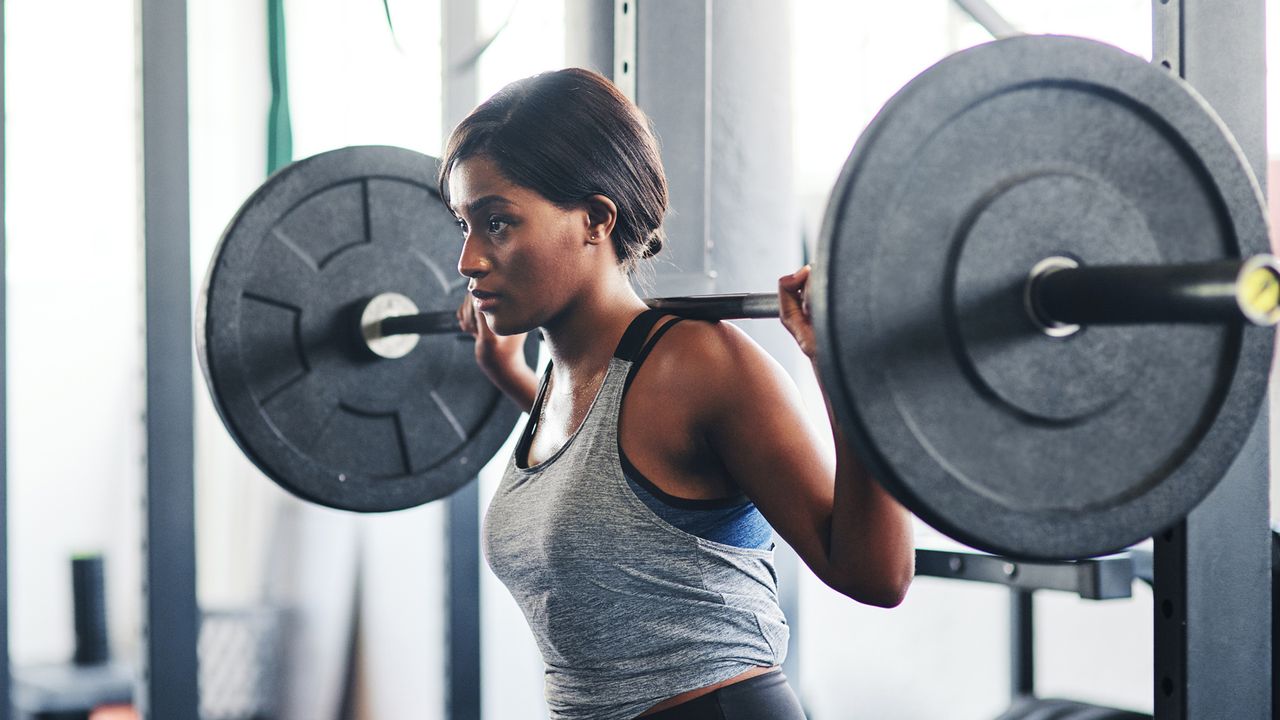 Cropped shot of a young woman working out with a barbell at the gym