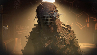 Man stood in a basement wearing a ghillie suit