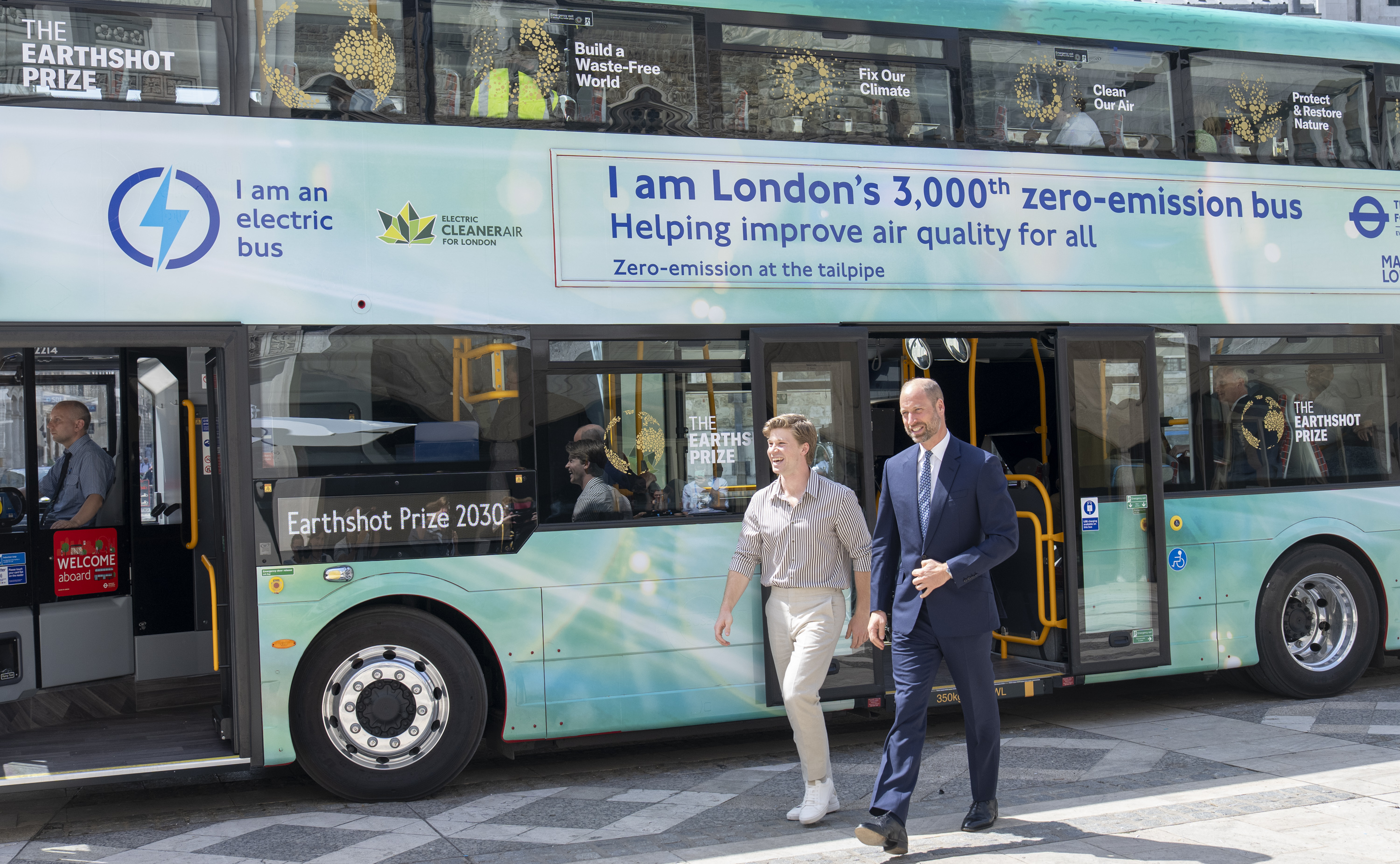 Prince William and Robert Irwin walking next to a London bus