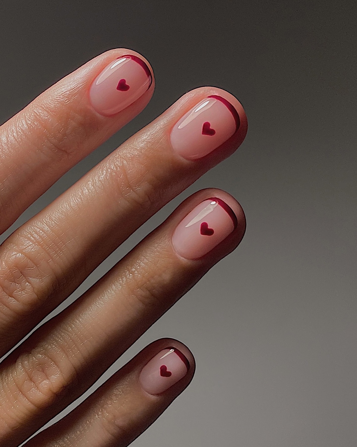 A burgundy French tip nail design with burgundy hearts