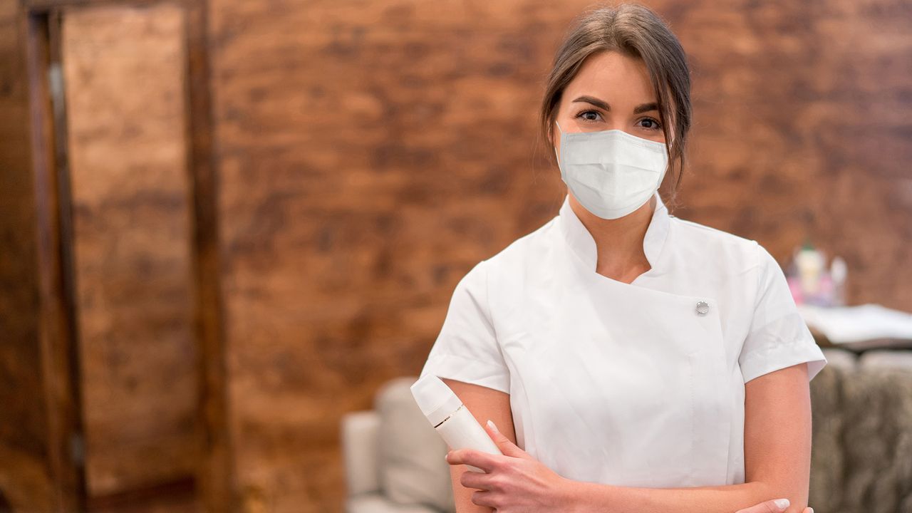 woman working in beauty salon wearing ppe