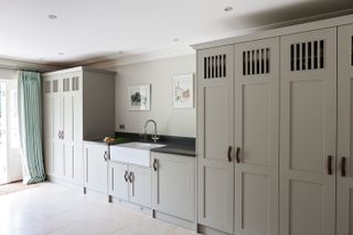 Utility room storage ideas showing large grey cabinets with a Belfast sink and long drapes