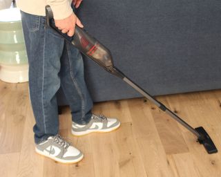 Camryn Rabideau using the Eufy HomeVac H30 vacuum on laminate flooring