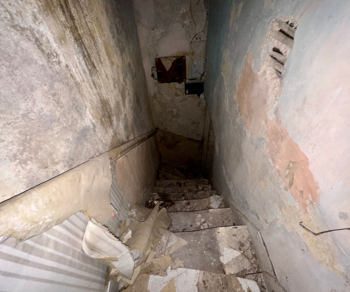 A dark staircase with crumbling walls
