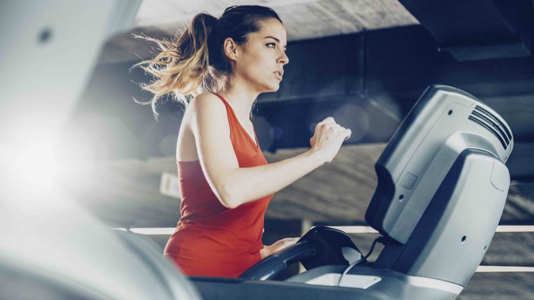 Woman in red vest running on treadmill