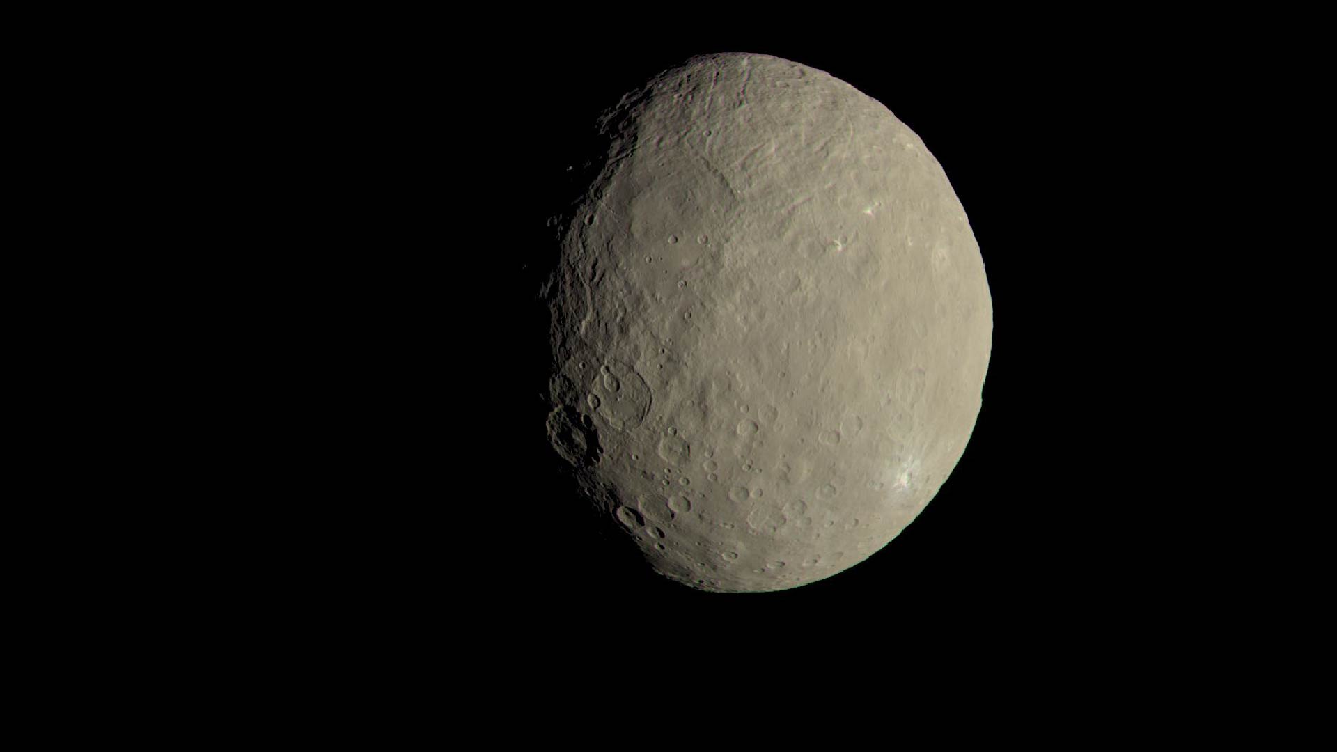 An image of Ceres. It is a grayish, cream colored planet with some craters.