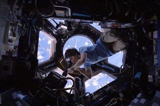 ESA astronaut Samantha Cristoforetti, inside the space station cupola, photographs the Earth in a scene from the IMAX film "A Beautiful Planet."