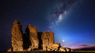 This picture shows a rock formation at the Salar de Tara in front of the Milky way at night. Also on the night sky is the planet venus visible at the horizon.