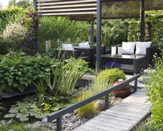 pond with decked outdoor lounge area and wooden pergola