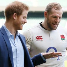 Prince Harry wearing a blue suit and talking to James Haskell wearing an England rugby uniform