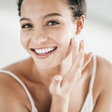 An image of a women putting cream on her face