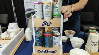 Shelf with a variety of ColdSnap pods on a table with a woman grabbing one from the top shelf