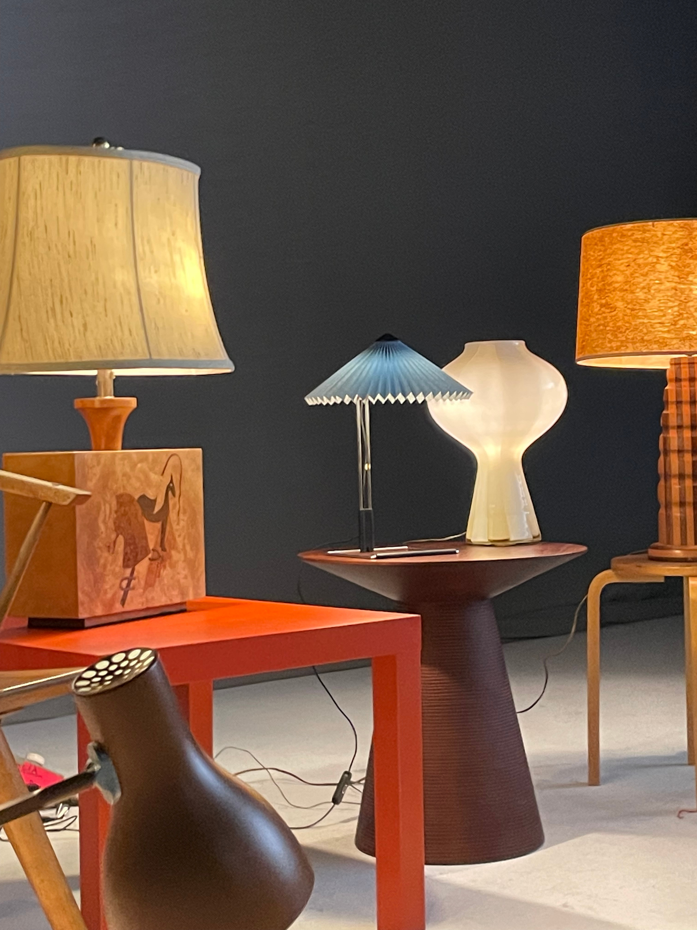 A series of interior shots of an art and objects-filled, dimly lit apartment, a museum's gallery rooms, an empty dance rehearsal room, and colorfully decorated office spaces.