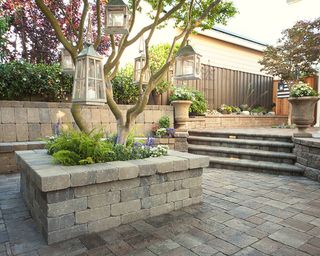 Patio with stone planter in the middle and low walls that double as seating