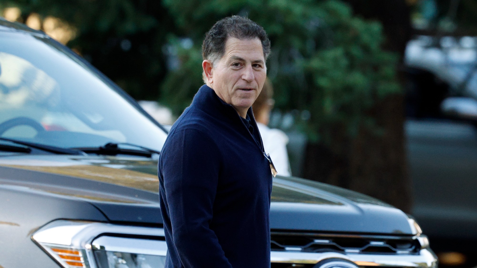 Michael Dell, CEO of Dell, walking past a car