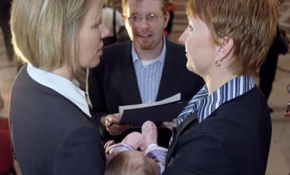 A same sex couple, holding their four-month-old baby, exchange wedding vows at City Hall in San Francisco in 2004