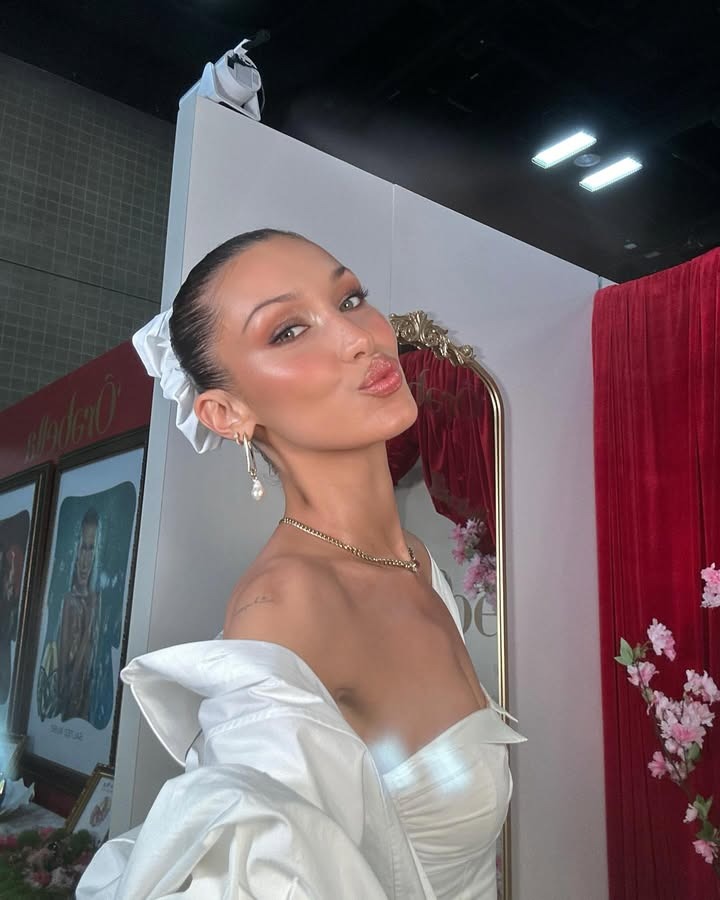 Bella Hadid taking a selfie wearing a slicked-back bun