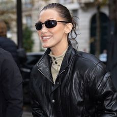 Bella Hadid wears oval sunglasses and a black leather jacket 