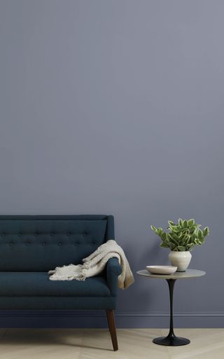 A dark blue couch against a "Cosmic Vibes" painted wall with Clare paint