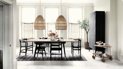 A large dining room with two large rattan pendant lights hanging over the table