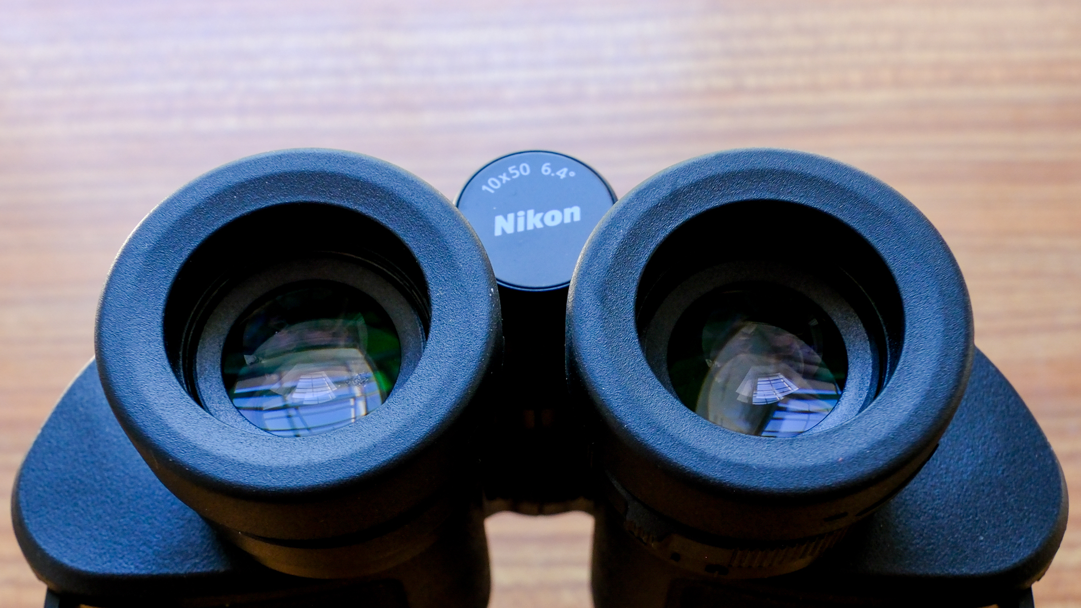 A closeup of the eyecups on the Nikon Action 10x50 binoculars on a wooden table.