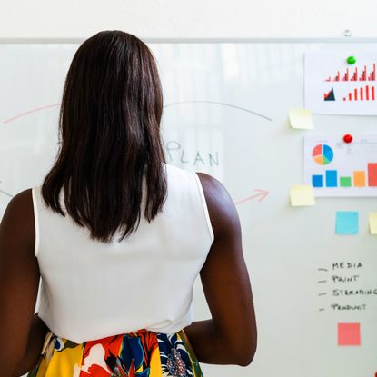 A woman in a white shirt looking at a whiteboard