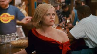Reese Witherspoon looks uncomfortable in a black and red one shoulder top in a dive bar in Sweet Home Alabama.