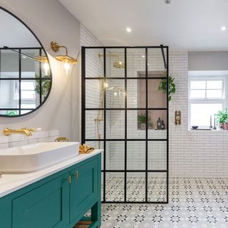Bathroom with black steel panelled shower wall, green vanity and grey and white patterned floor tiles, with small white brick wall tiles around the shower