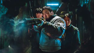 A still from Badland Hunters, Don Less is aiming a gun past the camera, with two young companions behind him