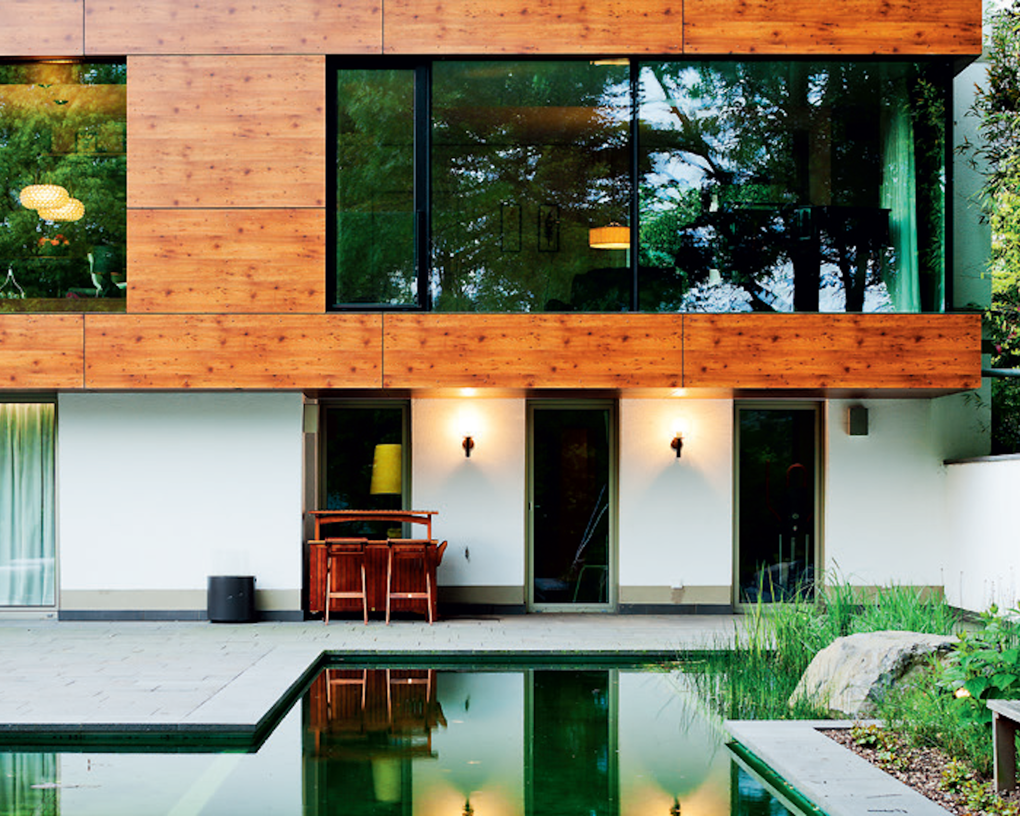 Contemporary home with wood cladding on first floor and white render on lower floor and large windows fitted with bird-protection glass