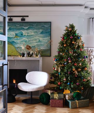 Christmas tree decorated with colorful ornaments, fireplace, cream boucle lounge chair, wave artwork