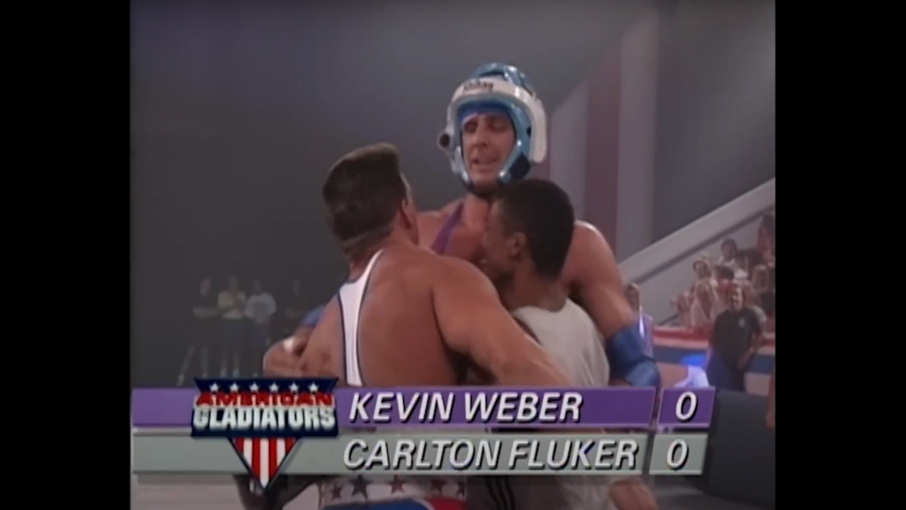 Carlton Fluker gets hugged by two Gladiators after a challenge in American Gladiators S4 E22.