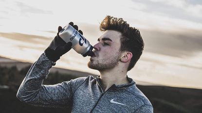 best supplements for runners: Pictured here, a runner having a drink from a bottle