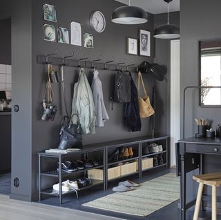 Grey walled hallway with a black clothing rack and ground storage with modern décor