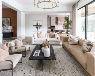 Large living room with couches placed over white and black fleck textured rug, with black marble coffee table in the center