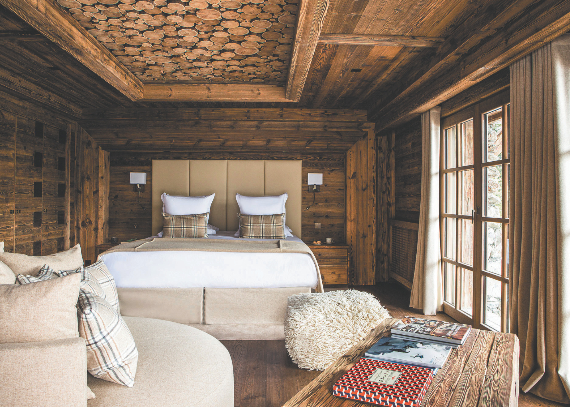 A suite at Refuge de la Traye with natural wood and cream tones with sections of circular wood fixed to the ceiling in a rectangular display