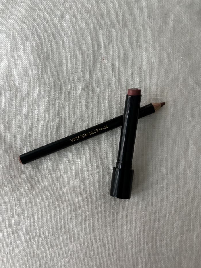 A Victoria Beckham Beauty lipstick and lip liner on a white linen background