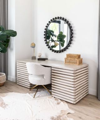 Light wooden dressing table with round mirror and white chair in space with shag rug