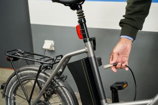 A person plugging in their e-bike ready to be charged